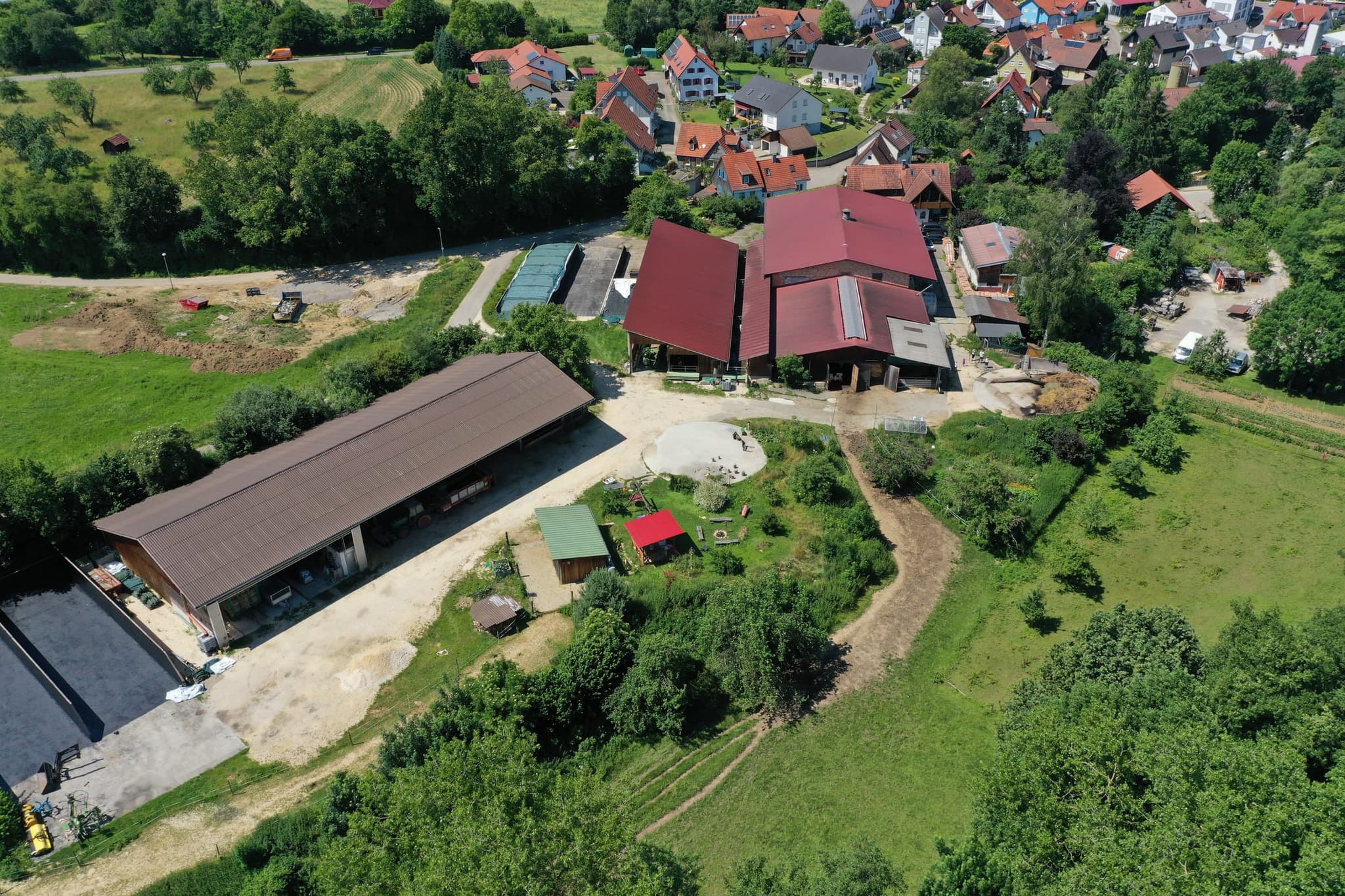Hofstelle und Maschinenhalle nebeneinander, im Vordergrund Fahrsilos und der Auslauf mit Sandfläche