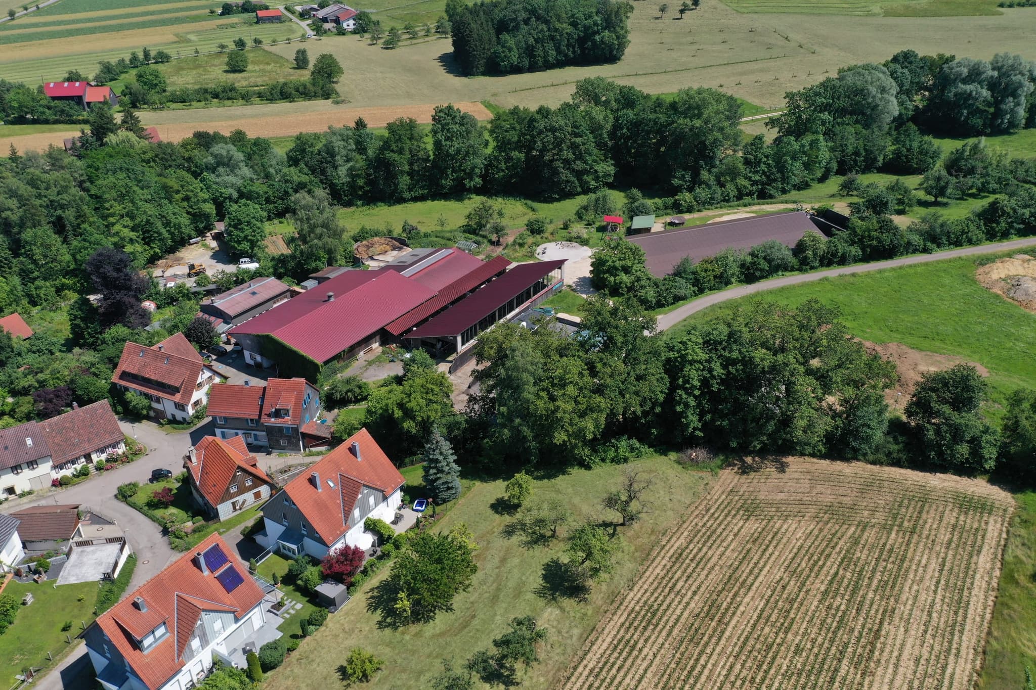 Der Offenstall mit seiner langen Traufseite, links die Hofgebäude, rechts der Acker