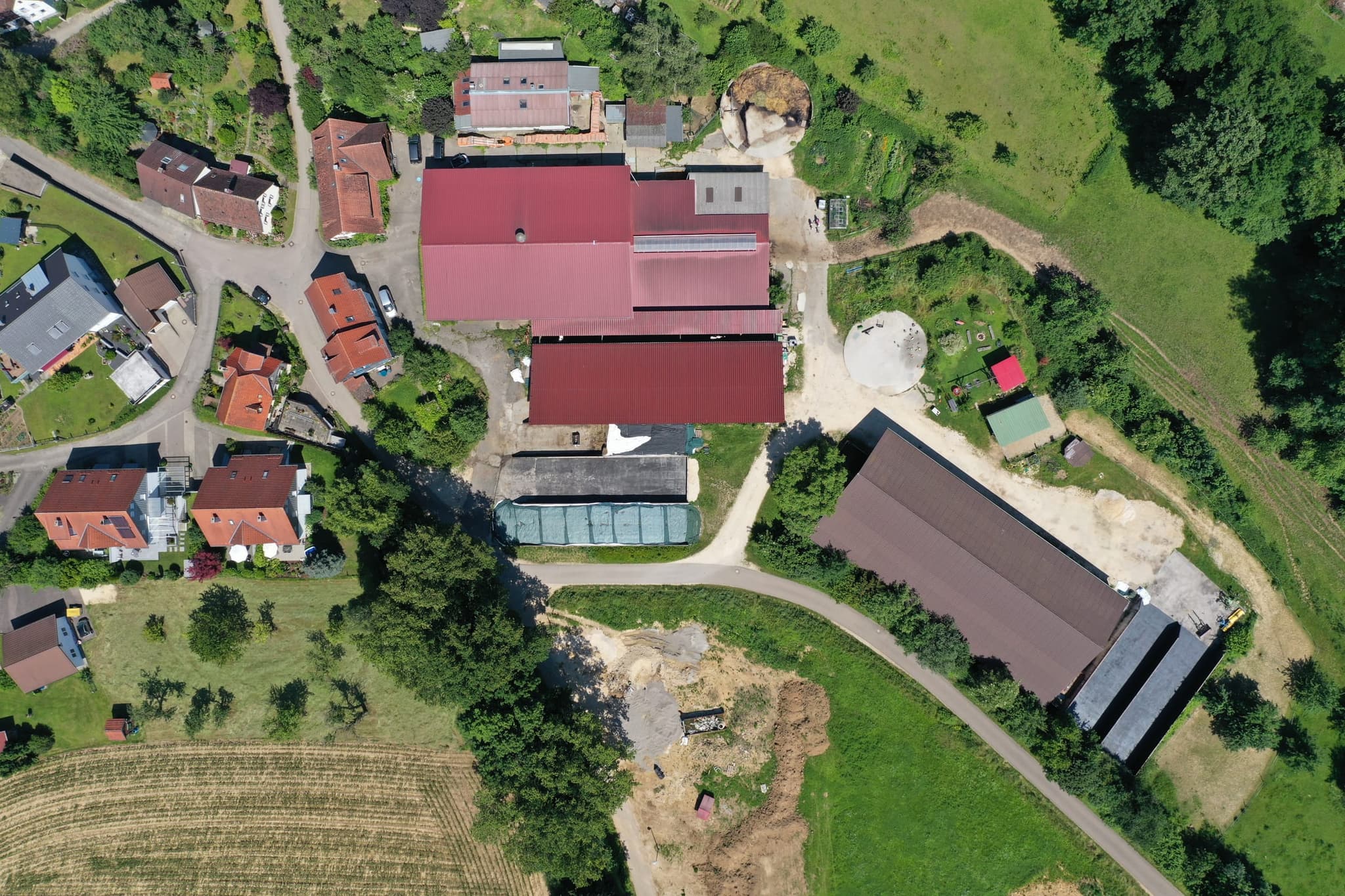 Senkrecht über der Hofstelle: Stalldächer, Fahrsilo, Auslauf und die Feldscheune am Weg