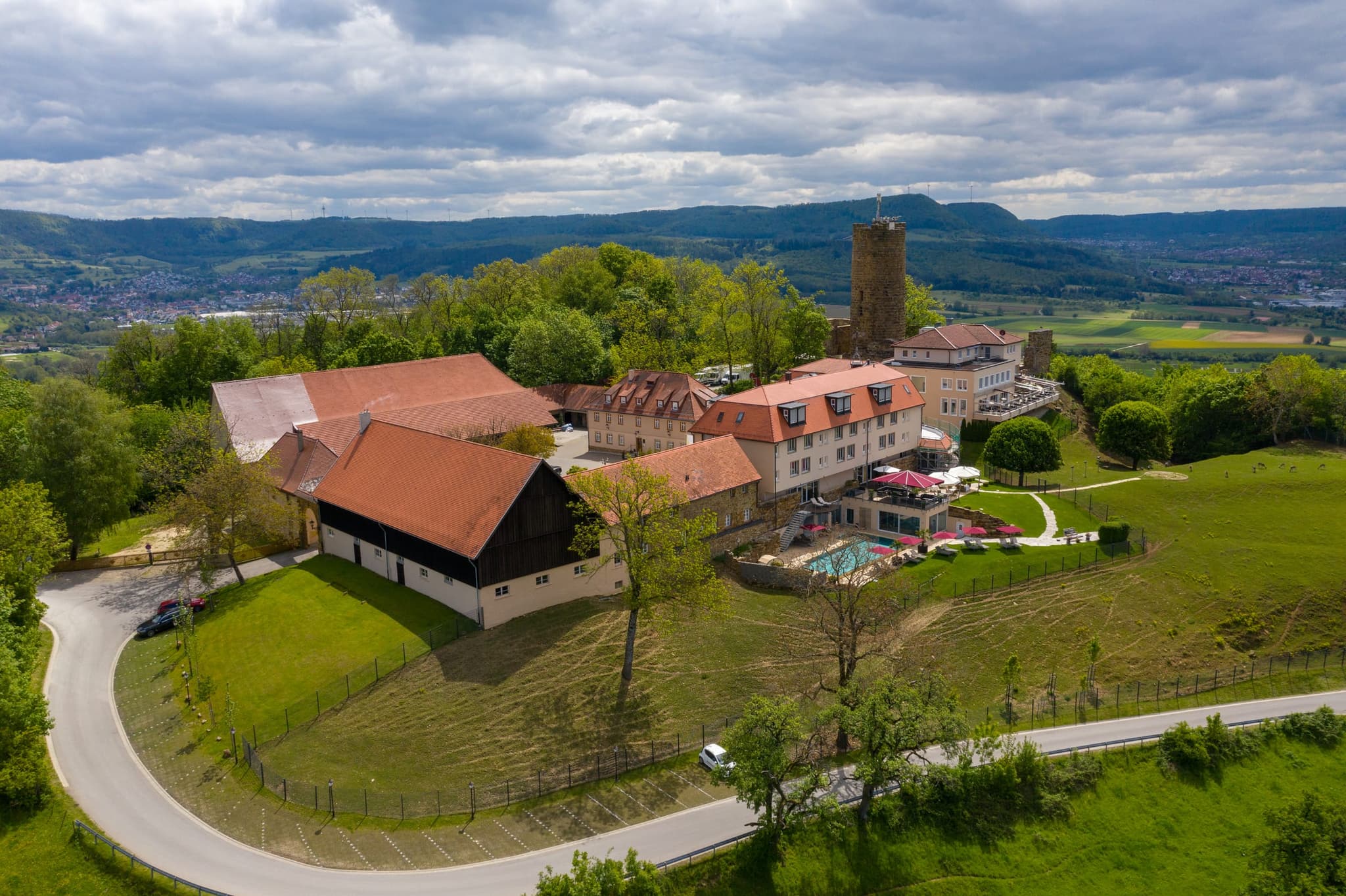 Burg Staufeneck von Nordwesten: Scheune mit dunklem Holzgiebel, Zufahrt und Stellplätze im Vordergrund