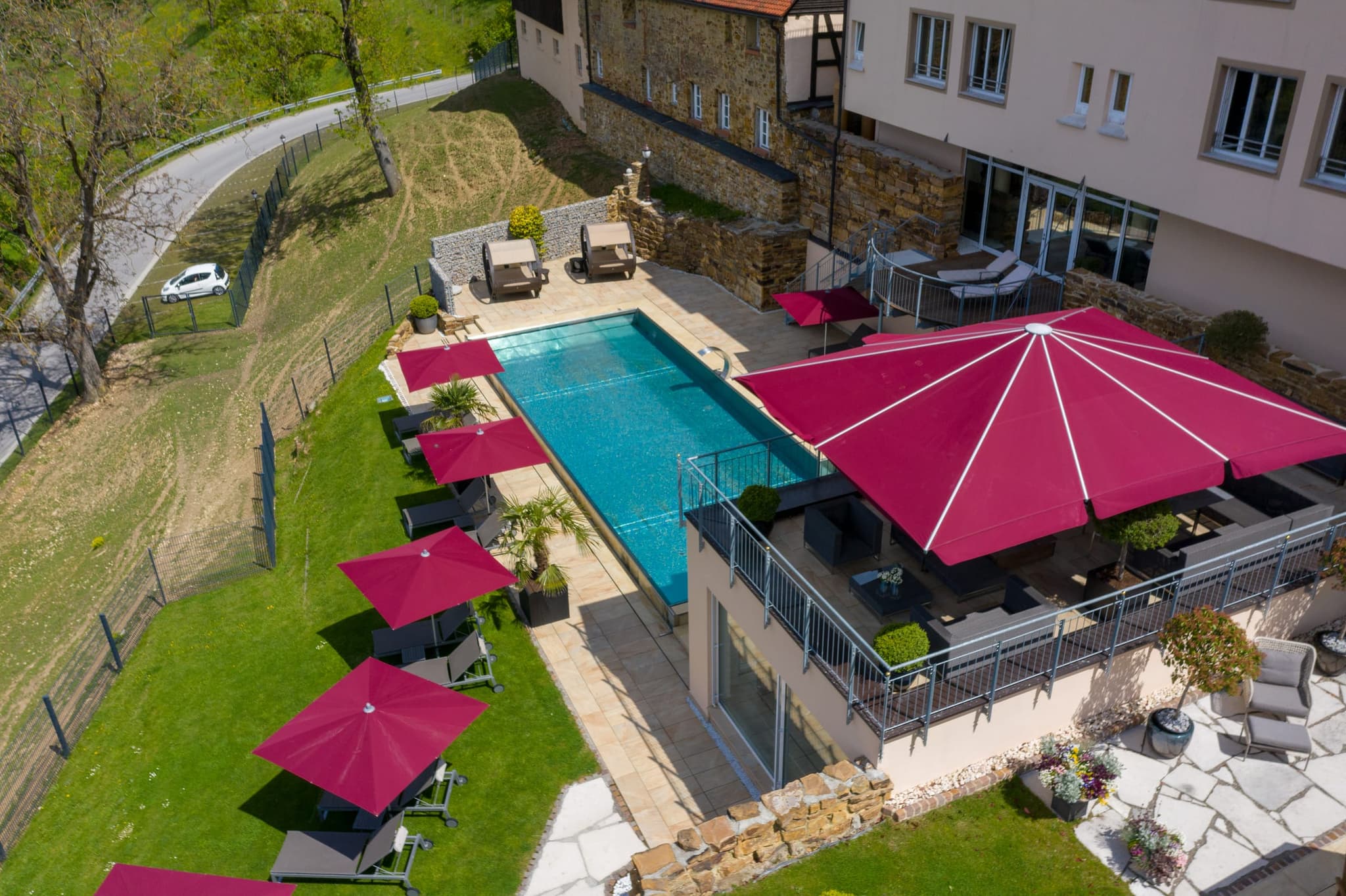 Naher Blick auf den Pool: türkisfarbenes Becken, Liegen und die pinkfarbenen Schirme der Terrasse
