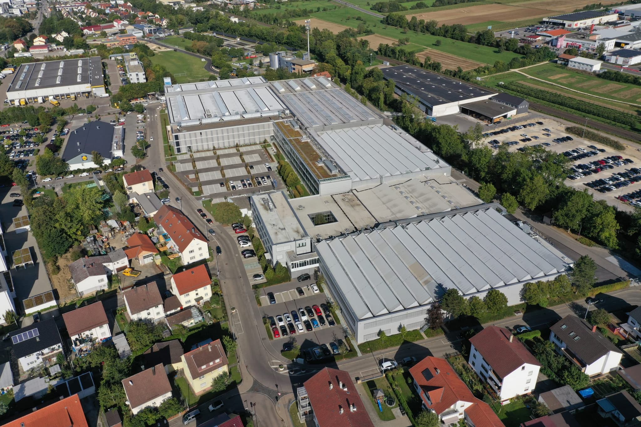 Das EMAG-Werk Salach von oben: Hallenreihen, begrüntes Bürogebäude und Mitarbeiterparkplätze