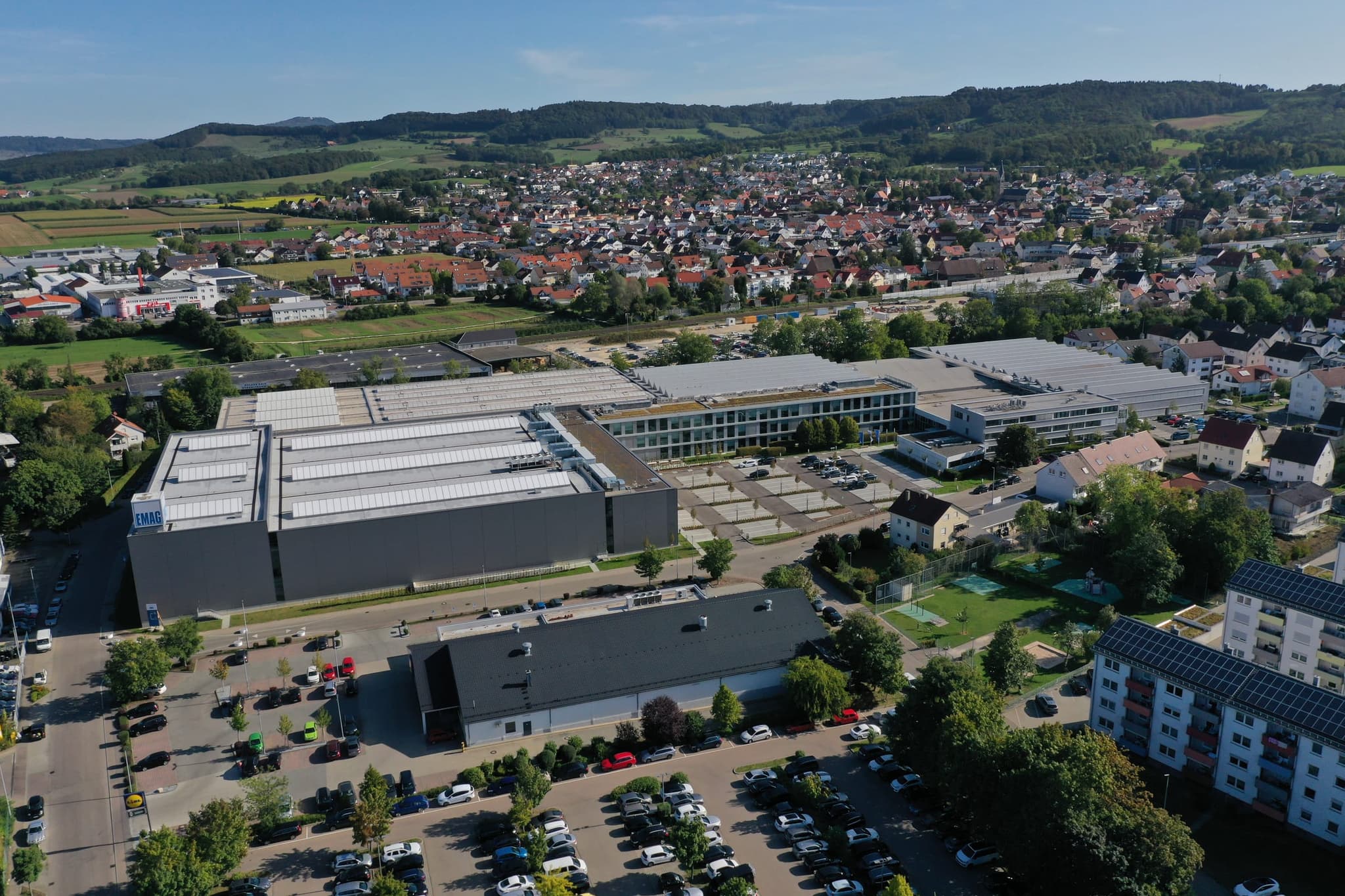 Werk und verglastes Bürogebäude im Zusammenhang, im Hintergrund Salach und der Albtrauf