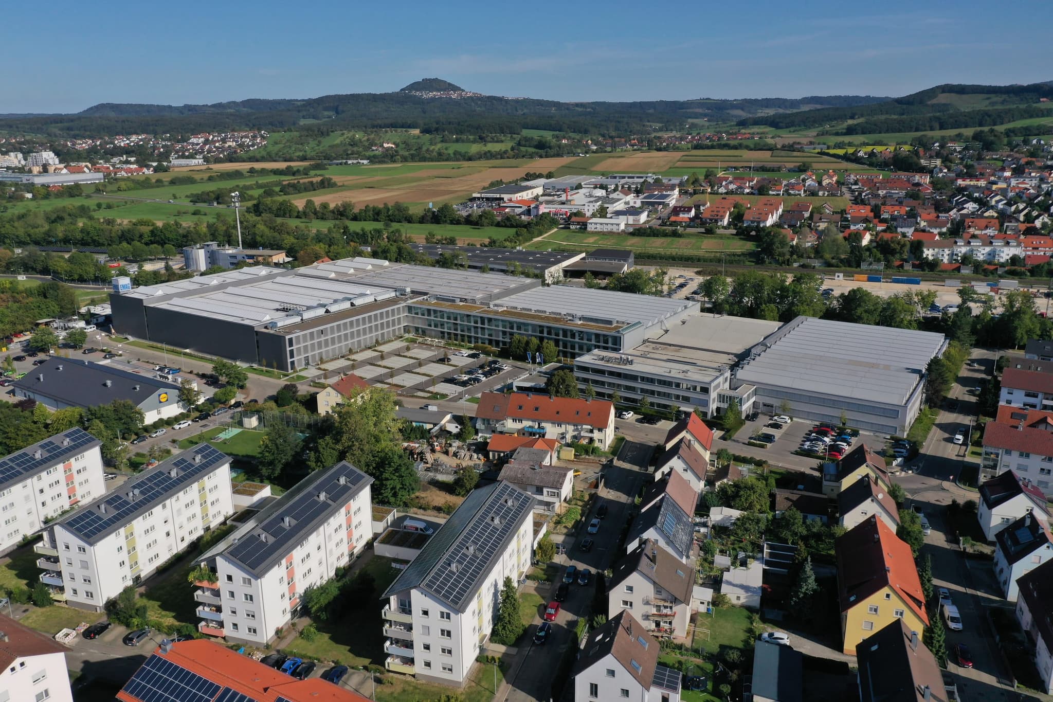 Das Werksgelände aus größerer Entfernung, im Hintergrund der Hohenstaufen über den Feldern