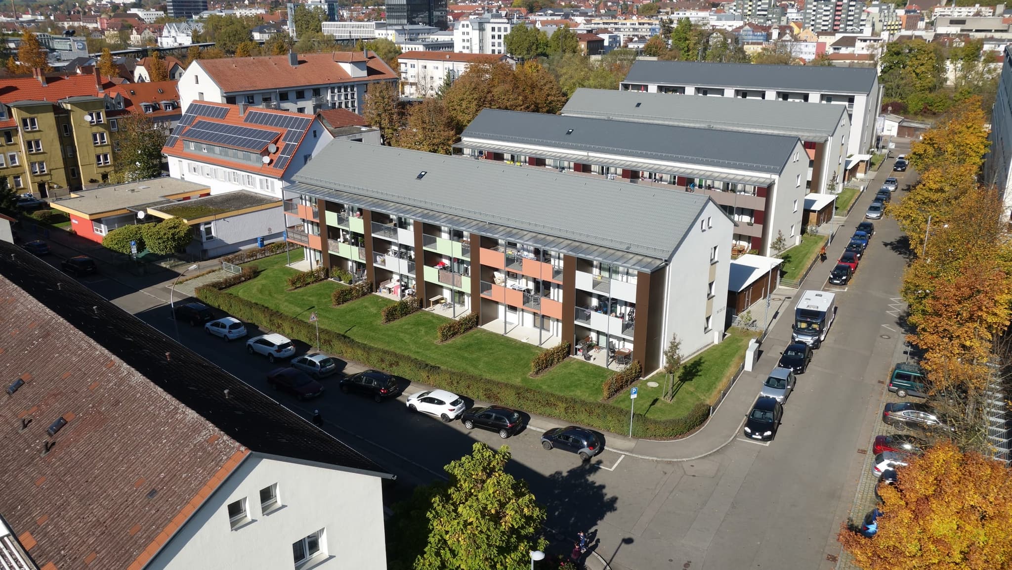 Wohnzeile in Göppingen mit farbigen Balkonfeldern und Glasvordach, dahinter die Innenstadt