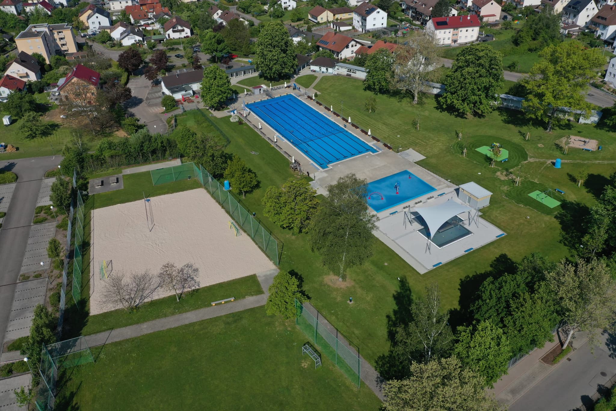 Das Schachenmayr-Freibad von oben: Schwimmerbecken, Planschbecken, Beachfeld und Spielwiese