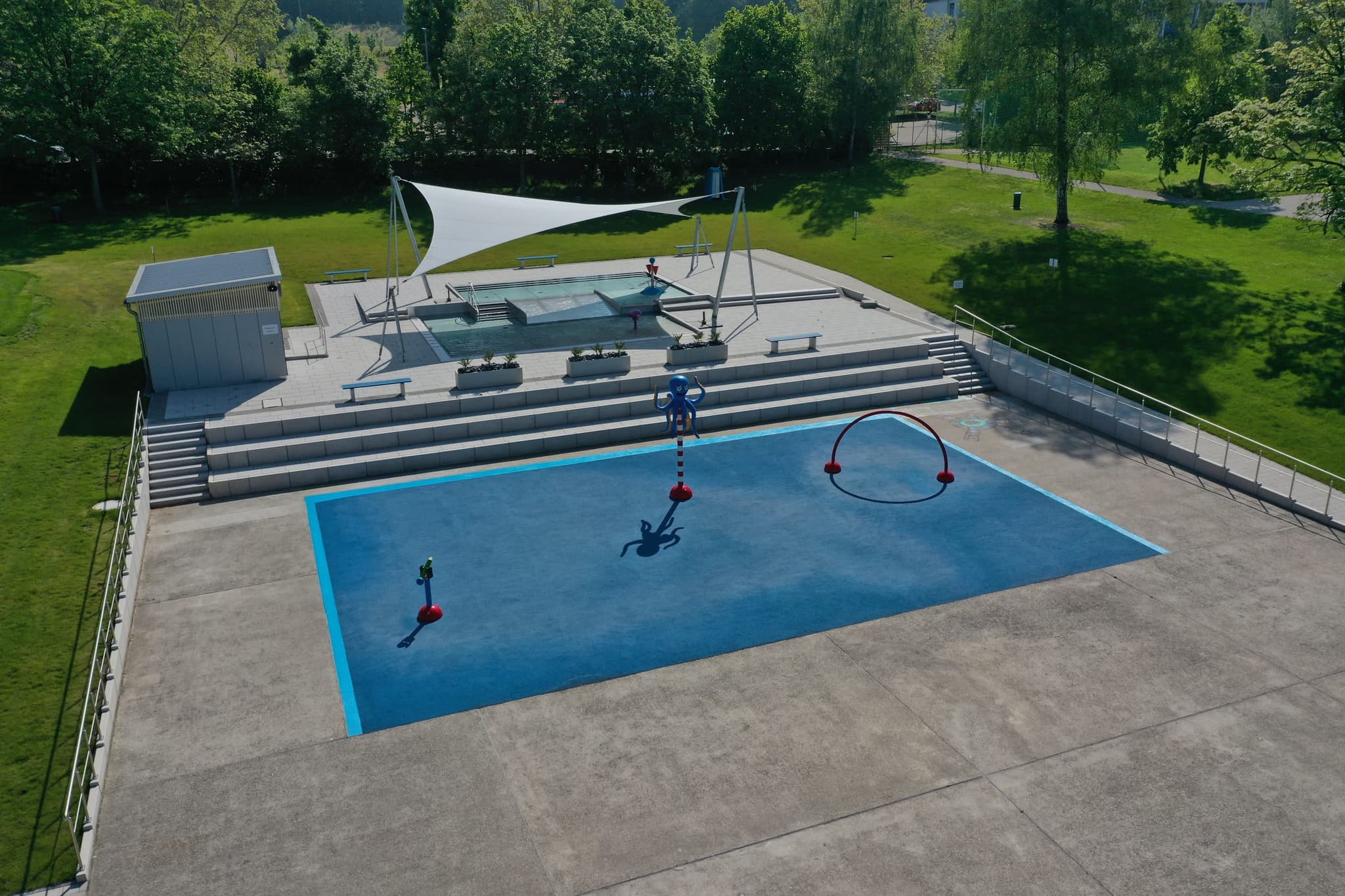 Der Kinderbereich mit Wasserspielfiguren, Sitzstufen und Sonnensegel über dem Kleinkindbecken