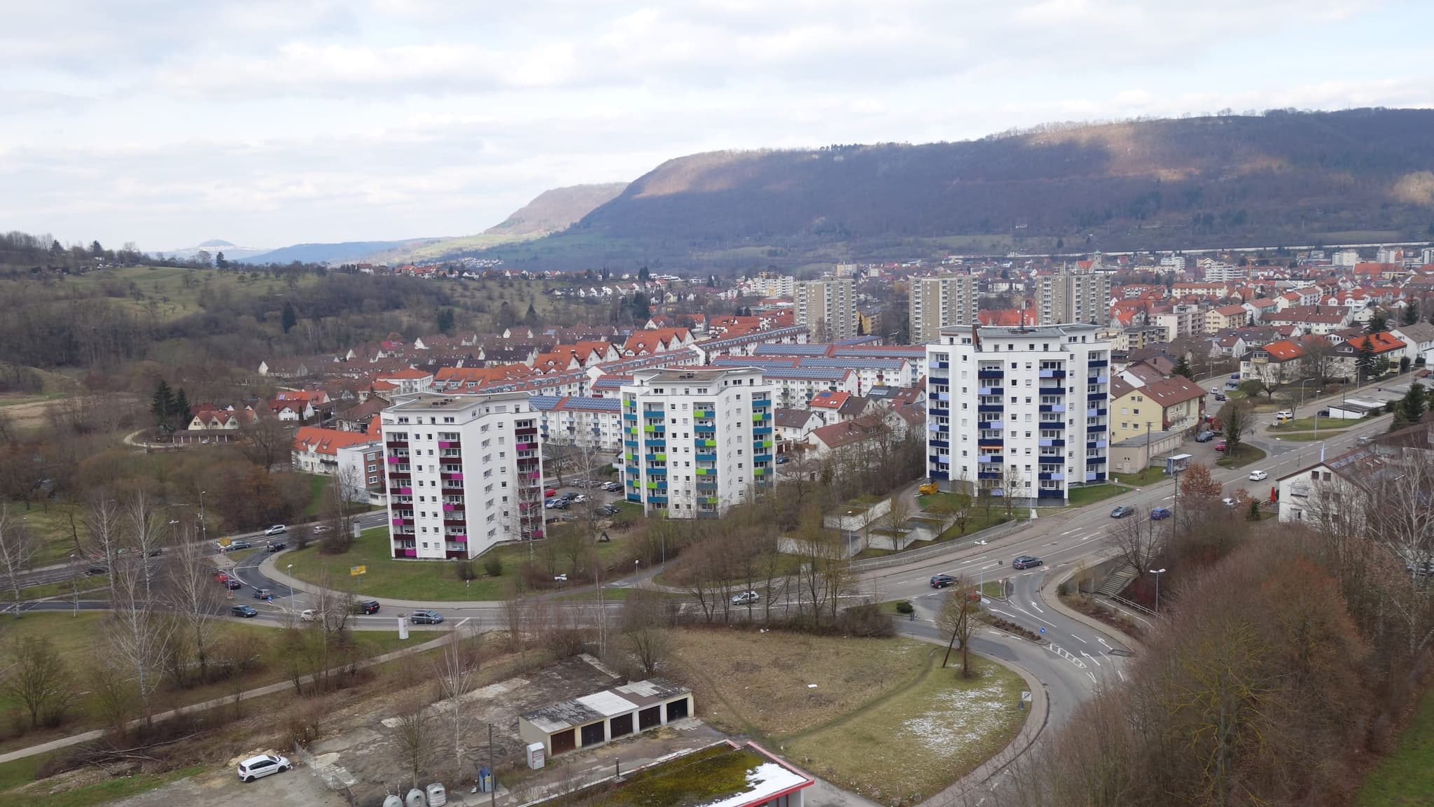 Die drei Wohnhochhäuser mit farbigen Balkonen, dahinter die Siedlung und der Albtrauf