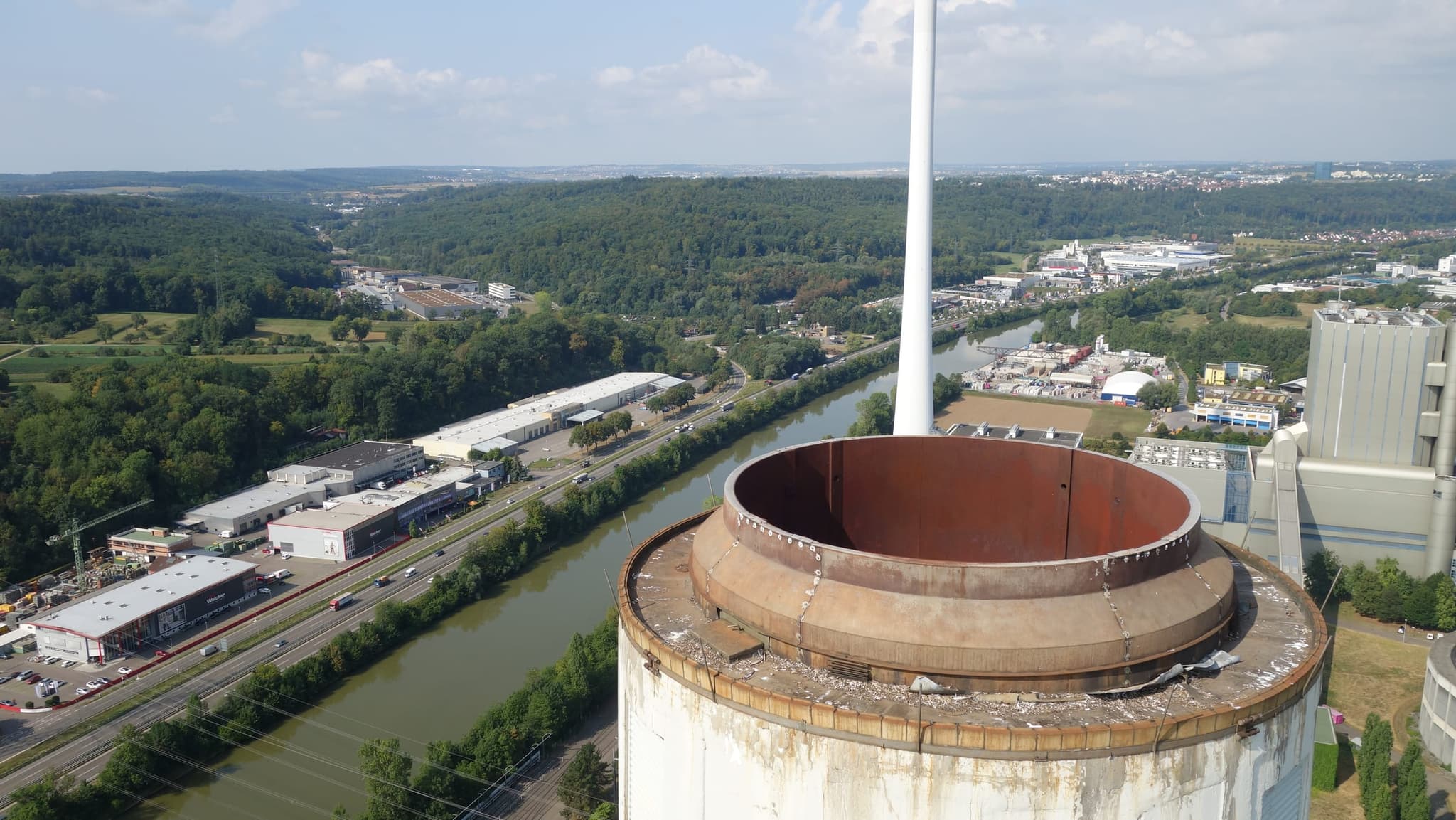Die offene Krone des Schornsteins aus der Nähe, dahinter der Neckar mit Bundesstraße und Gewerbegebiet