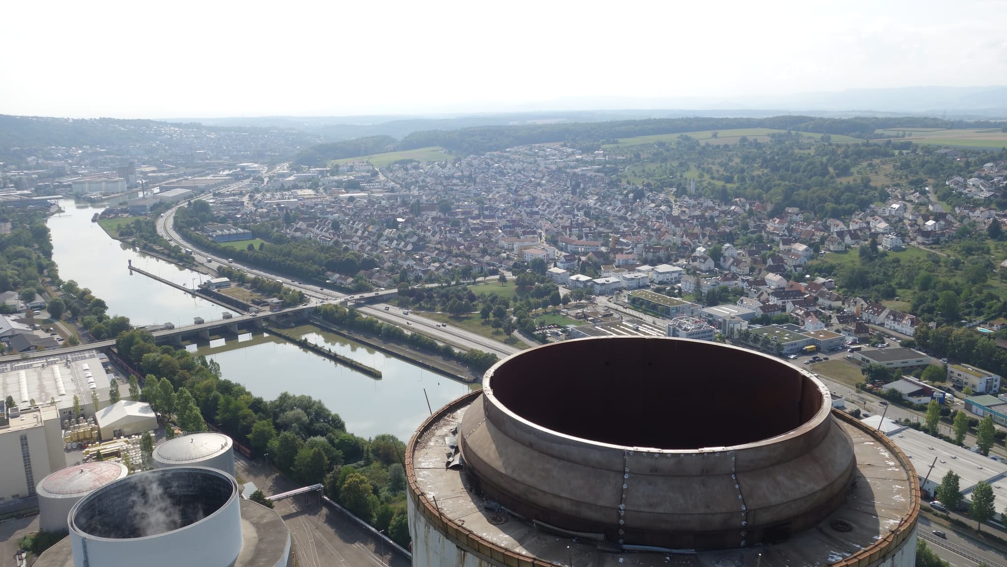 Blick über die Schornsteinkrone hinweg auf Neckarschleuse, Stadt und Talrand